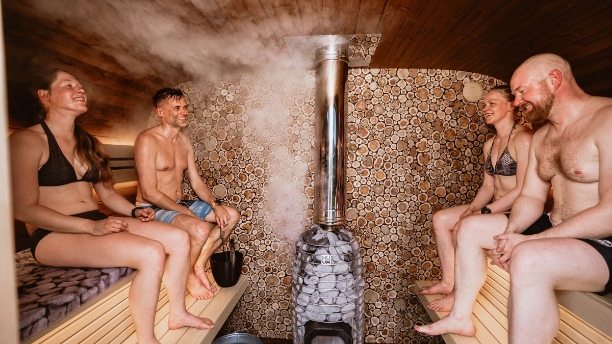Four friends in swimsuits chatting in a steamy wooden sauna
